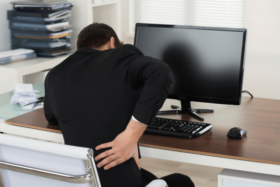 A man with back pain struggles to work at his desk